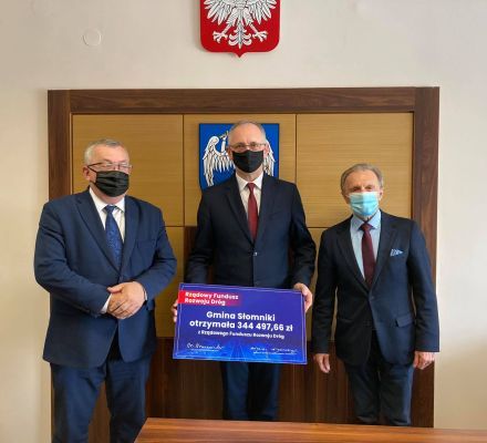 Burmistrz, minister Adamczyk i radny Tochowicz pozują trzymając czek