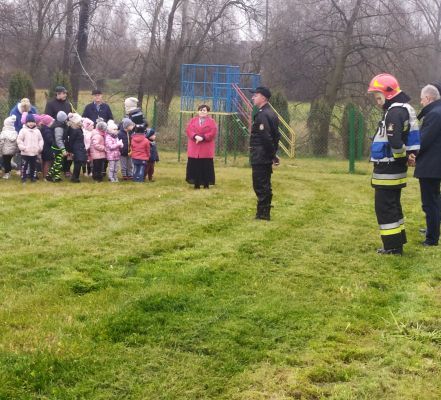 dzieci stojące na boisku podczas zbiórki ze strażakami i burmistrzem