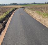 droga asfaltowa, po bokach rozciągają się pola uprawne